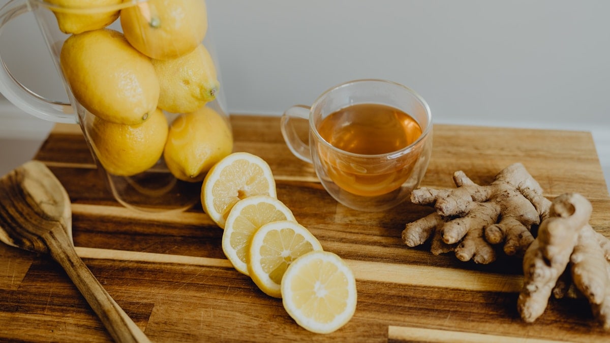a wooden cutting board topped with lemons and ginger